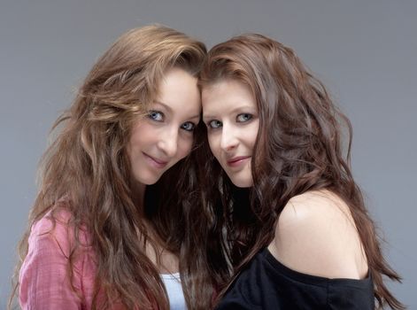 portrait of two young female friends looking - isolated on gray