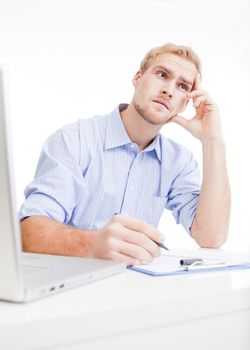 young man at desk in office thinking, contemplating