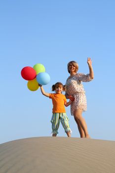 happy mother and daughter with balloons on beach