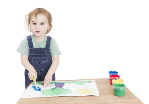 cute girl painting on small desk in grey background. studio shot