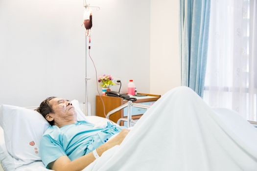 mature senior man Patient sleeping in hospital bed with blood infusion
