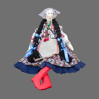 Sitting isolated handmade doll in the national Ukrainian costume with two pigtails