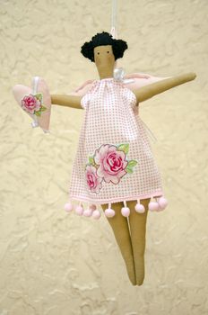 The Handmade doll in shot dress with wings and heart in the hand