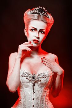 Red Queen with a crown and a corset, with make-up in studio shot