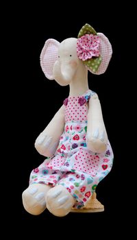 The Hand made soft toy elephant isolated in a jumpsuit sits