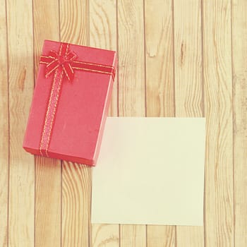 Red present box with blank note paper, retro filter effect