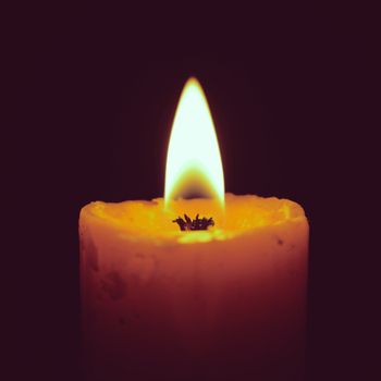 Burning candle on black with retro filter effect
