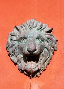 Water flow from lion statue on wall 