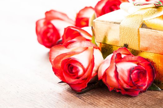 Golden gift box and bouquet of roses on the table