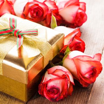 Golden gift box and bouquet of roses on the table