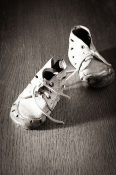 Old .worn baby shoes on the floor. Concept of poor childhood
