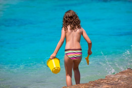 Kid girl rear view in beach tropical turquoise water with bucket and spade