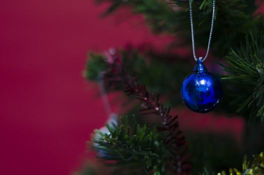 close up blue christmas ball on tree on red background