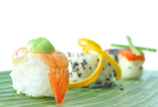 Closeup of fish and vegetable sushi snacks on a banana leaf 