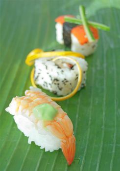 Closeup of fish and vegetable sushi snacks on a banana leaf 