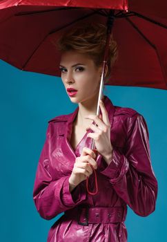 Young woman with umbrella on blue