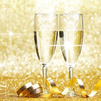 Two champagne glasses and decoration on golden stars background