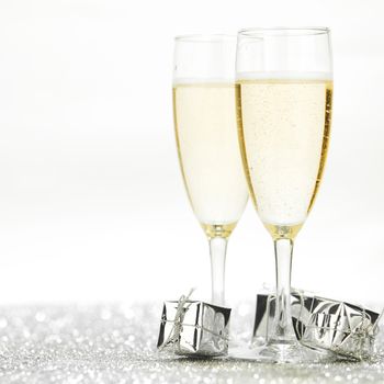Two champagne flutes and gifts on shiny background