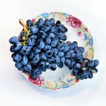 Grapes on plate isolated, with path in front of white background