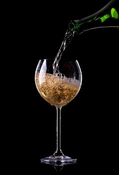 Champagne pouring from bottle into a glass on black background