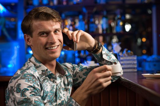 young man at the bar on the phone and drinking coffee