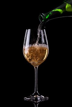 Champagne pouring from bottle into a glass on black background