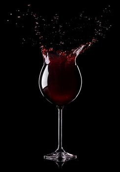 Wine splashing from a wine-glass on black background