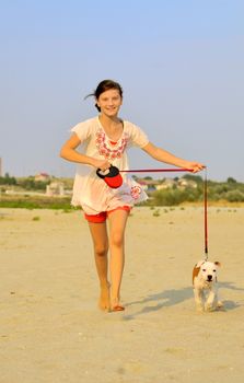 girl running with her dog on the sand on a summer day