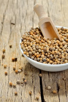 Coriander seeds in small ceramic pot, closeup on wooden table