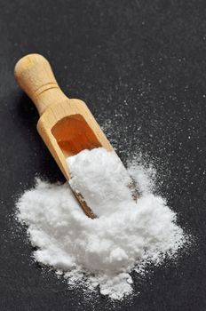 Wooden shovel with sodium bicarbonate on black background