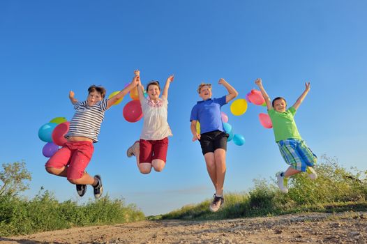 happy children jumping on field with balloons in summer time 