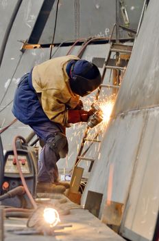 worker grinding metal inside of shipyard