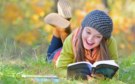 Beautiful young woman reading a book in autumn day