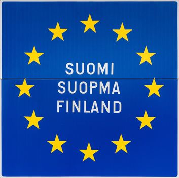 Sign in Utsjoki, northern Lapland, on the border with Norway spells the name of Finland in Finnish, in Saami language and in English. All on the classic European blue background with golden stars.