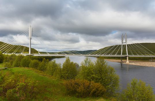 Modern suspension bridge with two H-shaped towers in the northern tip of Finnish Lapland. View from the Finnish shore.