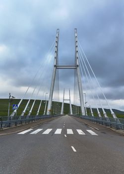 Modern suspension bridge with two H-shaped towers in the northern tip of Finnish Lapland links Finland and Norway. View from Finland along the street surface.