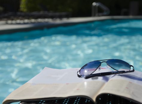 Sunglasses on a magazine by the swimming pool