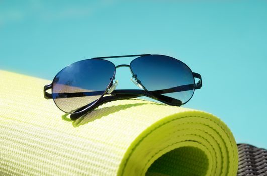Sunglasses on the yoga rug by the swimming pool