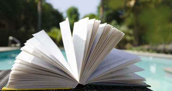 Open book by the swimming pool