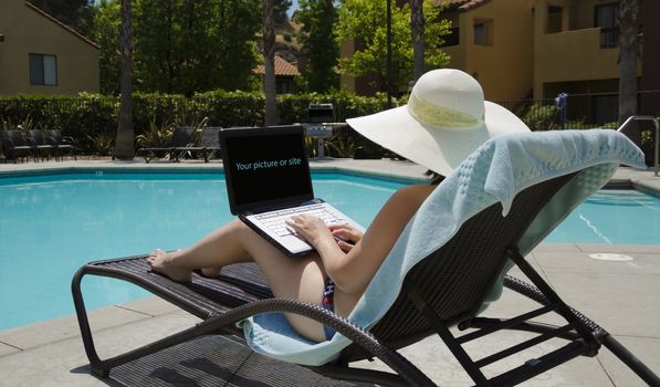Girl in a summer heat typing on laptop by the swimming pool