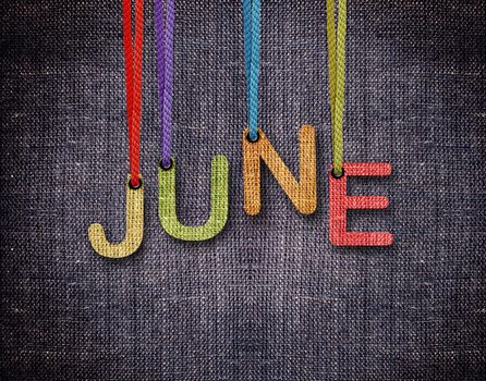June letters hanging strings with blue sackcloth background.