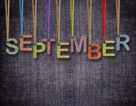 September letters hanging strings with blue sackcloth background.
