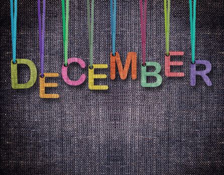 December letters hanging strings with blue sackcloth background.