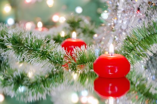 Christmas new year decoration  with red candles on the mirrored surface and bokeh on a green background