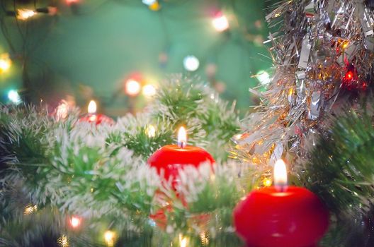 Christmas new year decoration with  red candles and lights of garlands on a green background