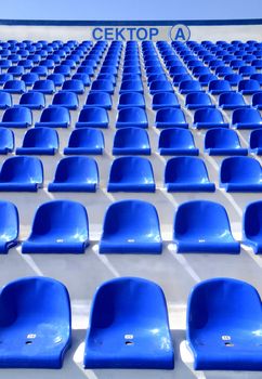 the blue empty plastic stadium chairs with the inscription: "Sector A"