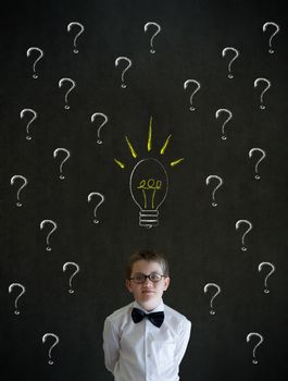Thinking boy dressed up as business man questioning ideas on blackboard background