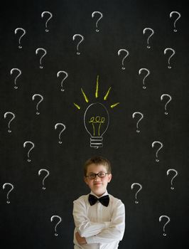 Thinking boy dressed up as business man questioning ideas on blackboard background