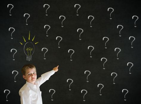 Pointing boy dressed up as business man questioning ideas on blackboard background