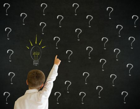 Pointing boy dressed up as business man questioning ideas on blackboard background